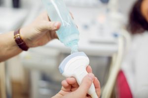 A sonographer is applying gel on an ultrasound probe before the ultrasound scan in London