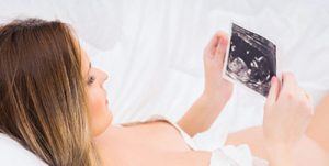 A woman is looking at ultrasound photo after a gender scan in London