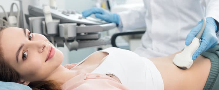 A woman is having a private abdominal and urinary tract ultrasound in London. The sonographer is resting the probe on her abdomen