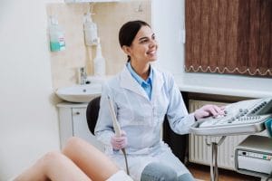 A sonographer is getting ready to perform a transvaginal scan on a woman lying on her back with her knees bend