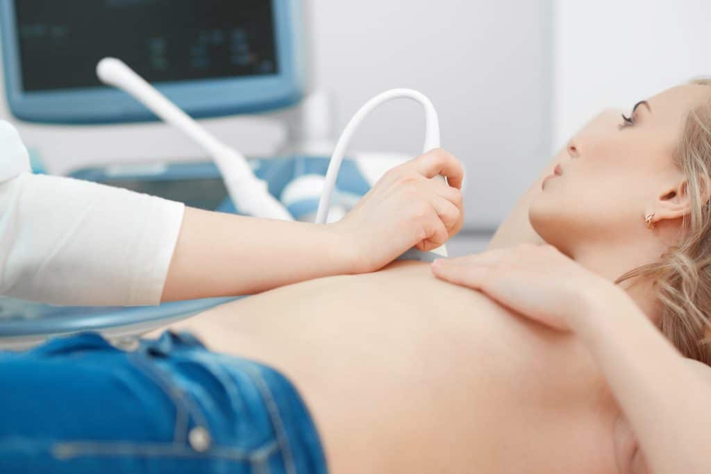A woman is lying on an examination couch having a private breast ultrasound scan in private ultrasound clinic in London