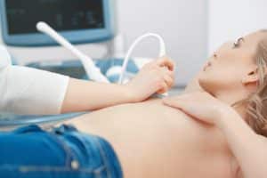 A woman is lying on an examination couch having a private breast ultrasound scan in private ultrasound clinic in London